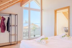 una camera da letto con una grande finestra e un letto bianco di Helle Wohnung mit Seeblick a Tutzing