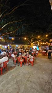 a group of people sitting at tables in a restaurant at night at Chalé Premium no Centro da Vila in Itaúnas