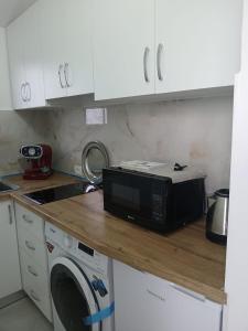 a kitchen with a microwave on a counter with a washing machine at Osmenaj Studios in Vlorë