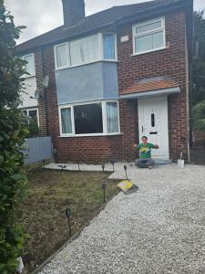a man kneeling in front of a house with a frisbee at Manas house in Manchester