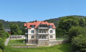 Villa Gloriette - BoutiqueAppartements am Wörthersee في بويرشاك آم فورثيرسي: منزل قديم بسقف احمر على ارض خضراء