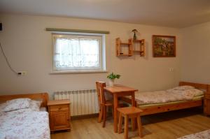 a bedroom with two beds and a table and a window at Gospodarstwo Agroturystyczne Stajnia Grudki Energylandia Zator in Zator