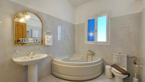 a bathroom with a tub and a sink and a toilet at SUNSET VILLA MILOS pera triovasalos in Triovasálos +34 photos