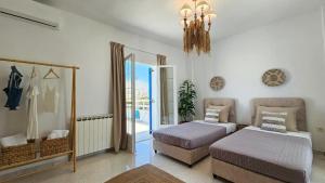 a bedroom with two beds and a chandelier at SUNSET VILLA MILOS pera triovasalos in Triovasálos