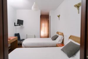 a hotel room with two beds and a desk at Hostal Arlanzón in Burgos