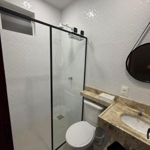 a bathroom with a toilet and a glass shower at Triplex Flecheiras in Flecheiras