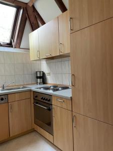 a kitchen with wooden cabinets and a stove top oven at Ferienhaus Lisa am Silbersee in Frielendorf +15 photos