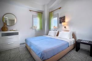 a bedroom with a bed with a blue comforter and a mirror at Dionisos Resort in Pefkochori