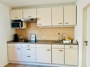 a kitchen with white cabinets and a sink at Ferienwohnung Moselverliebt in Schweich