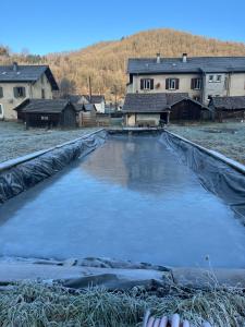 a large pool of water in a field with houses at gite du Breuchin 2 in La Longine