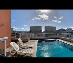 a balcony with a swimming pool and two lounge chairs at Apto no Itaguá - Varanda Gourmet e Lazer completo in Ubatuba