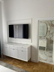 a white bathroom with a television on a wall at GOLDENGREEn in Sibiu