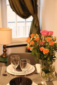 a table with a vase of flowers and wine glasses at Rolli House in Genova