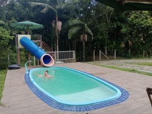 a person in a pool with a slide at Trento Chalés in Nova Trento
