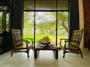deux chaises et une table devant une fenêtre dans l'établissement Ayubowan Eco Lodge, à Kandy