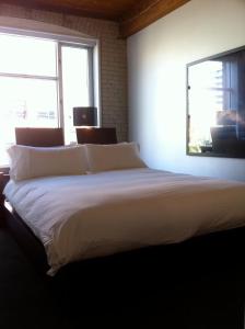 a large white bed in a room with two windows at Hotel Ocho in Toronto