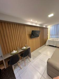 ein Schlafzimmer mit einem Bett und einem Tisch und einem Fernseher in der Unterkunft Eco Miragem Residence - Porto de Galinhas in Porto De Galinhas