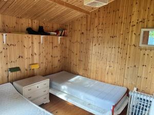 a room with two beds in a wooden wall at Cosy little summer house in Slagelse
