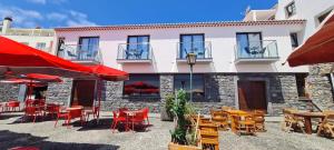 a group of tables and chairs in front of a building at Casa Linda Baía in Porto da Cruz