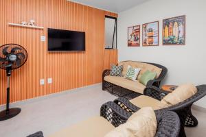 a living room with two chairs and a flat screen tv at Casa Pé na Areia a 10m da Praia! Imperdível! in Olivença +25 photos