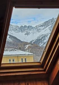 a view of a snow covered mountain from a window at Mansarda Bardonecchia in Bardonecchia