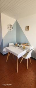 a table in a room with a clock on the wall at Appartement-1- prive, terrasse, parking et jardin in Le Boulou