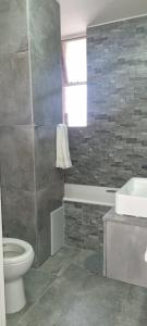 a bathroom with a toilet and a tub and a sink at Oceanic Unit 67 - North Beach in Durban