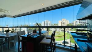 a dining room with a view of a large window at Pé na areia mod 5 Riviera de São Lourenço in Bertioga