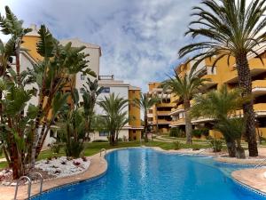 a resort with a swimming pool and palm trees at Seaside Park Haven in Punta Prima