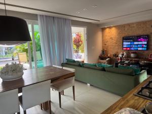 ein Wohnzimmer mit einer grünen Couch und einem Tisch in der Unterkunft Casa à Beira-Mar em Itacimirim, Viva o Paraíso! in Camassari