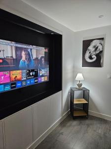 une pièce avec une grande télévision à écran plat fixée au mur dans l'établissement Le Cocon de Marine, à Triel-sur-Seine 2 autres photos