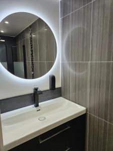 une salle de bains avec un lavabo et un miroir dans l'établissement Le Cocon de Marine, à Triel-sur-Seine