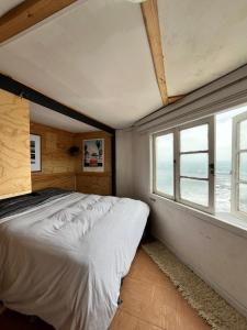 um quarto com uma cama grande e uma janela em El Barco Pichilemu em Pichilemu