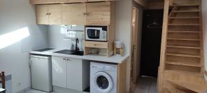 a small kitchen with a washing machine and a microwave at Petit Appartement dans les Arbres in Carcans