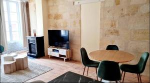 a living room with a table and chairs and a television at 4- Hypercentre, FREE Parking, Clim, Wifi, Netflix in Libourne