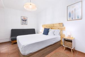 Un dormitorio con una cama grande y una silla. en 2BR El Cotillo House - Private Terrace, en Cotillo