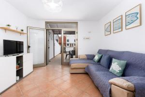 Una sala de estar con un sofá azul y un televisor en 2BR El Cotillo House - Private Terrace, en Cotillo