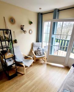 - un salon avec deux chaises et une porte coulissante en verre dans l'établissement Charmant Duplex en bord de Dordogne - Argentat- Corrèze, à Argentat