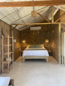 une chambre avec un lit dans une pièce aux murs en bois dans l'établissement Cabana Cachandó, à Corumbau