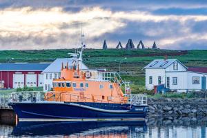 an orange boat docked in the water next to houses at The Nest in Raufarhöfn