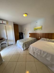 a hotel room with two beds and a desk at Condomínio Residencial Thermas Place Apto 119 in Caldas Novas