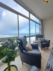 a living room with two blue chairs and a large window at Ocean Tides - 2 Adults & 4 Kids ONLY in Umdloti