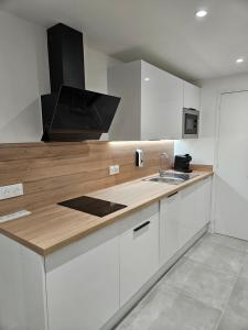 a kitchen with white cabinets and a wooden counter top at Le Cocon de Marine in Triel-sur-Seine