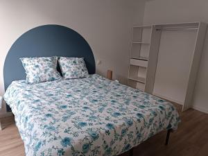 a bedroom with a bed with a blue and white comforter at Appartement moderne et bohème in Vittel