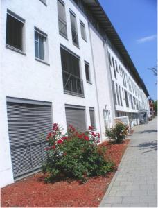 a white building with two garage doors and some flowers at Re-in City-DE in Regensburg