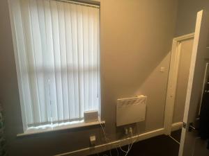 La salle de bains est pourvue d'une fenêtre avec des stores. dans l'établissement Ashton Apartment, à Ashton-under-Lyne