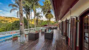 a deck with chairs and palm trees and a pool at Pousada Boutique Mercedes in Extrema