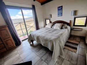 a bedroom with a bed and a large window at ArribadelValle - Casas de Altura in Potrerillos
