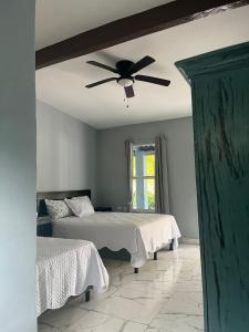 Un dormitorio con dos camas y un ventilador de techo. en Boni Beach, en Miravalles