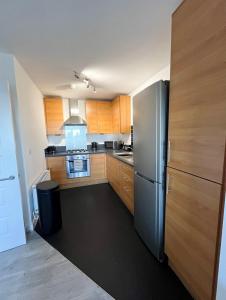 Una cocina con gabinetes de madera y un refrigerador de acero inoxidable. en Home From Home Let, en Stifford